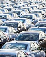 Rows of a new cars parked in a distribution center on a car factory on a sunny day. photo
