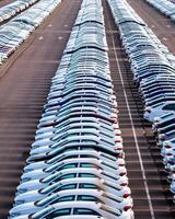 Rows of a new cars parked in a distribution center on a car factory on a sunny day. photo
