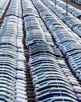 Rows of a new cars parked in a distribution center on a car factory on a sunny day. photo