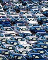Rows of a new cars parked in a distribution center on a car factory on a sunny day. photo