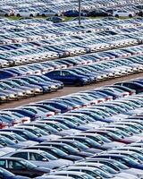 Rows of a new cars parked in a distribution center on a car factory on a sunny day. photo