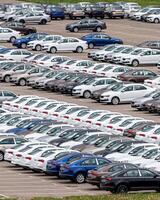 Rows of a new cars parked in a distribution center of a car factory. photo