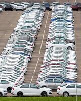 Rows of a new cars parked in a distribution center of a car factory. photo
