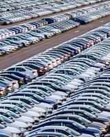 Rows of a new cars parked in a distribution center on a car factory on a sunny day. photo