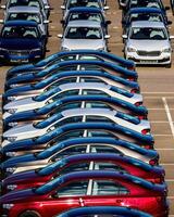 Rows of a new cars parked in a distribution center on a car factory on a sunny day. photo