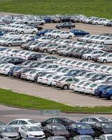 Rows of a new cars parked in a distribution center of a car factory. photo
