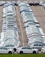 Rows of a new cars parked in a distribution center of a car factory. photo