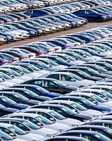 Rows of a new cars parked in a distribution center on a car factory on a sunny day. photo