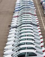 Rows of a new cars parked in a distribution center of a car factory. photo