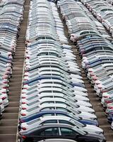 Rows of a new cars parked in a distribution center of a car factory. photo
