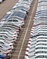 Rows of a new cars parked in a distribution center of a car factory. photo