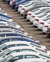 Rows of a new cars parked in a distribution center of a car factory. photo