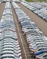 Rows of a new cars parked in a distribution center of a car factory. photo