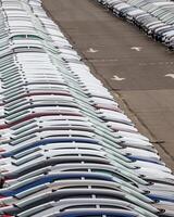 Rows of a new cars parked in a distribution center of a car factory. photo