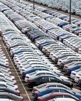 Rows of a new cars parked in a distribution center of a car factory. photo