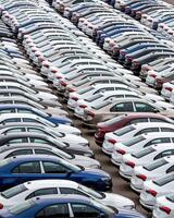 Rows of a new cars parked in a distribution center of a car factory. photo