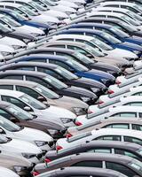 Rows of a new cars parked in a distribution center of a car factory. photo