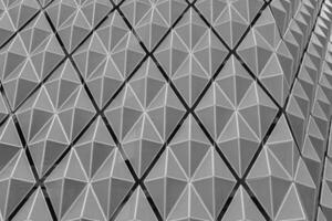 Fragment of a modern building. Abstract geometric background. Part of the facade of a skyscraper with metal diamond-shaped grids. photo