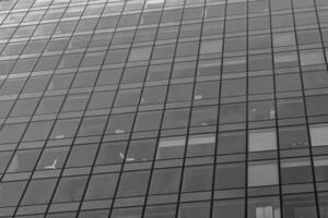 Fragment of a modern office building. Abstract geometric background. Part of a skyscraper with glass windows. Black and white. photo