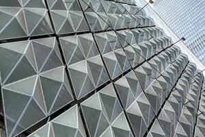 Fragment of a modern building. Abstract geometric background. Part of the facade of a skyscraper with metal diamond-shaped grids. photo