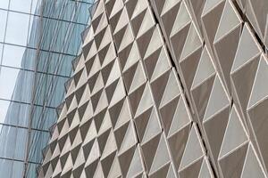 Fragment of a modern building. Abstract geometric background. Part of the facade of a skyscraper with metal diamond-shaped grids. photo