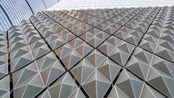 Fragment of a modern building. Abstract geometric background. Part of the facade of a skyscraper with metal diamond-shaped grids. photo