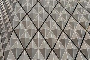 Fragment of a modern building. Abstract geometric background. Part of the facade of a skyscraper with metal diamond-shaped grids. photo
