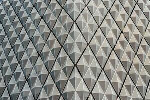 Fragment of a modern building. Abstract geometric background. Part of the facade of a skyscraper with metal diamond-shaped grids. photo