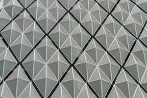 Fragment of a modern building. Abstract geometric background. Part of the facade of a skyscraper with metal diamond-shaped grids. photo
