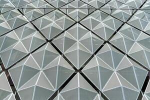 Fragment of a modern building. Abstract geometric background. Part of the facade of a skyscraper with metal diamond-shaped grids. photo