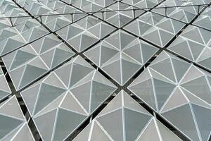 Fragment of a modern building. Abstract geometric background. Part of the facade of a skyscraper with metal diamond-shaped grids. photo