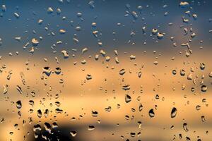Raindrops on a window with a sunset sky in the background. photo