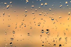 Raindrops on a window with a sunset sky in the background. photo
