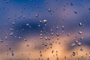 Raindrops on a window with a sunset sky in the background. photo
