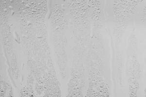 Rain drops on window glasses surface with gray sky background . Natural backdrop of raindrops. Overlay for design. The concept of bad rainy weather. photo