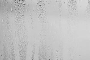 Rain drops on window glasses surface with gray sky background . Natural backdrop of raindrops. Overlay for design. The concept of bad rainy weather. photo
