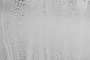 Rain drops on window glasses surface with gray sky background . Natural backdrop of raindrops. Overlay for design. The concept of bad rainy weather. photo