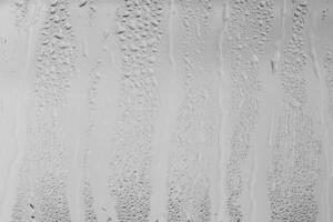 Rain drops on window glasses surface with gray sky background . Natural backdrop of raindrops. Overlay for design. The concept of bad rainy weather. photo