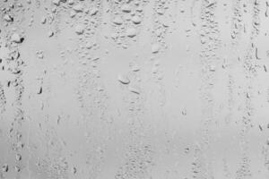 Rain drops on window glasses surface with gray sky background . Natural backdrop of raindrops. Overlay for design. The concept of bad rainy weather. photo