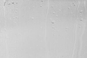 Rain drops on window glasses surface with gray sky background . Natural backdrop of raindrops. Overlay for design. The concept of bad rainy weather. photo