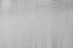 Rain drops on window glasses surface with gray sky background . Natural backdrop of raindrops. Overlay for design. The concept of bad rainy weather. photo