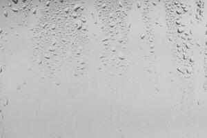 Rain drops on window glasses surface with gray sky background . Natural backdrop of raindrops. Overlay for design. The concept of bad rainy weather. photo