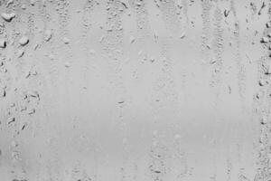 lluvia gotas en ventana lentes superficie con gris cielo antecedentes . natural fondo de gotas de lluvia. cubrir para diseño. el concepto de malo lluvioso clima. foto
