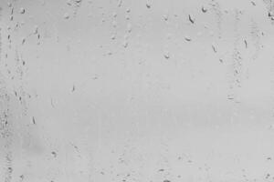 Rain drops on window glasses surface with gray sky background . Natural backdrop of raindrops. Overlay for design. The concept of bad rainy weather. photo