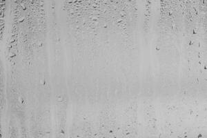 Rain drops on window glasses surface with gray sky background . Natural backdrop of raindrops. Overlay for design. The concept of bad rainy weather. photo