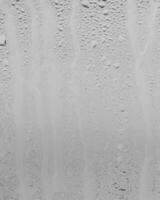 Rain drops on window glasses surface with gray sky background . Natural backdrop of raindrops. Overlay for design. The concept of bad rainy weather. photo