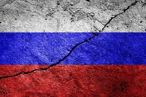 Russian Federation flag on cracked concrete wall. The concept of crisis, default, economic collapse, pandemic, conflict, terrorism or other problems in the country. Abstract disaster symbol. photo