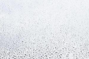 Rain drops on window glasses surface with gray sky background . Natural backdrop of raindrops. Abstract overlay for design. The concept of rainy weather. photo