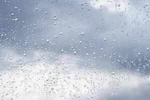 Rain drops on window glasses surface with cloudy background . Natural backdrop of raindrops. Abstract overlay for design. The concept of rainy weather. photo