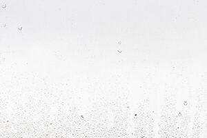 Rain drops on window glasses surface with gray sky background . Natural backdrop of raindrops. Abstract overlay for design. The concept of rainy weather. photo